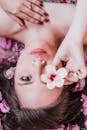 Elegant photoshoot featuring a woman holding a pink flower amidst petals.